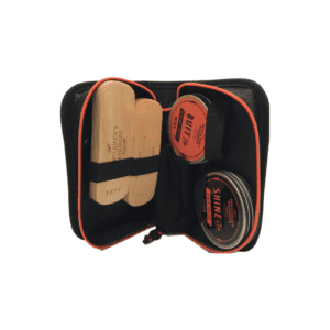 A fabric case unzipped and open, revealing two shoe shine brushes, two containers of shoe polish, and a cloth